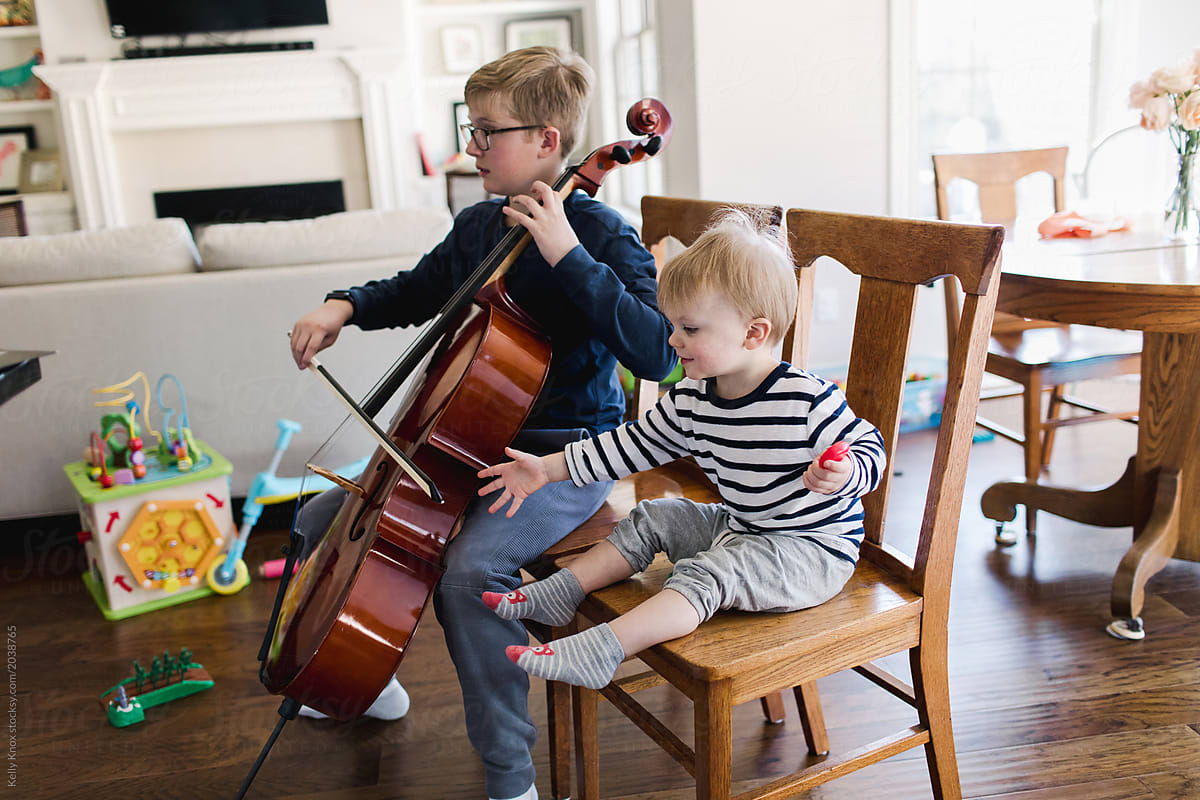 middle schooler attempts to practice his cello with toddler brother nearby