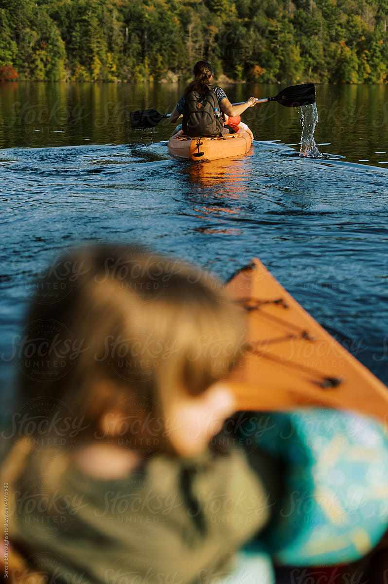 Two kayakers with children on a lake