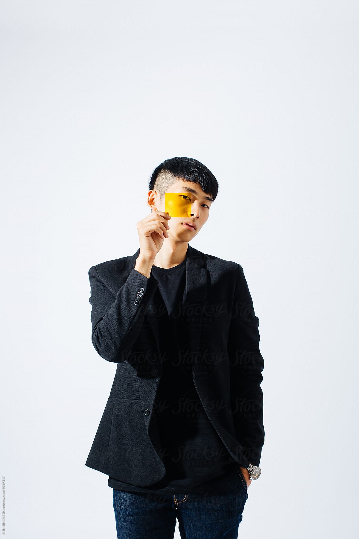 Portrait of an asian man holding a yellow glass in front his face.