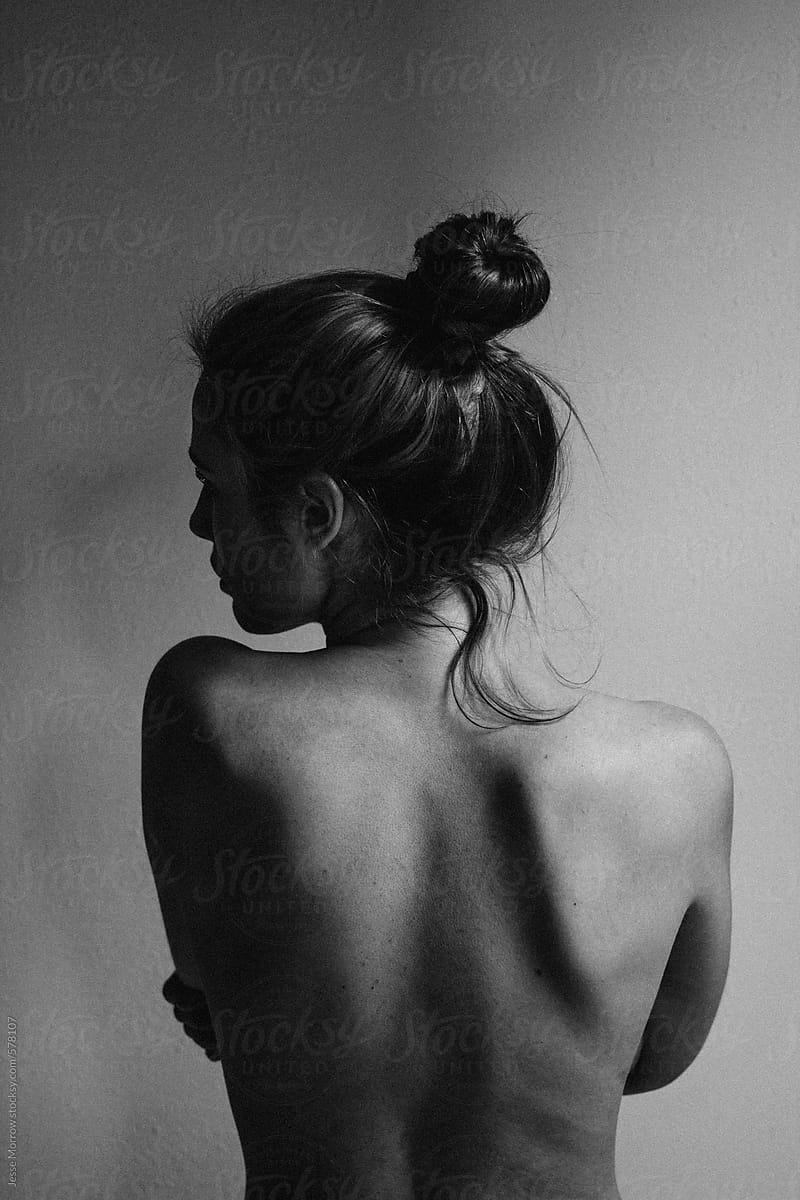 young woman with bare back towards camera intimate studio black and white