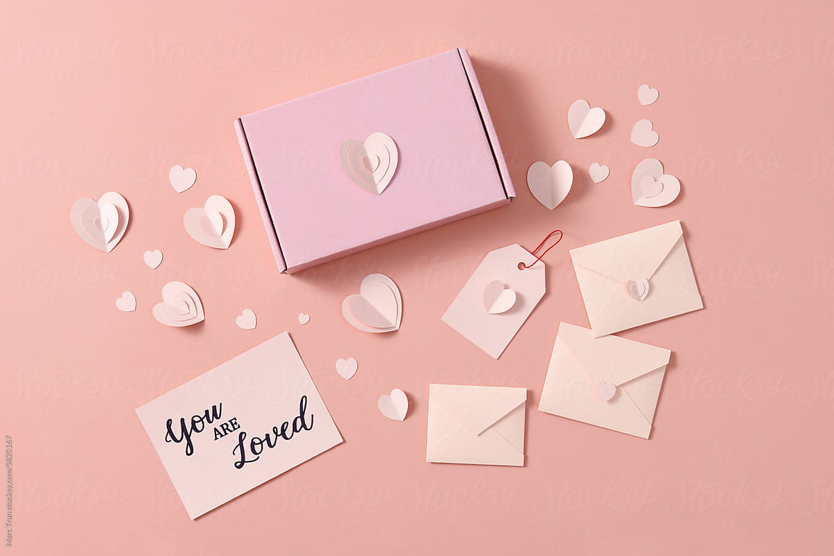 Creative flat lay of paper envelope with hearts around on beige