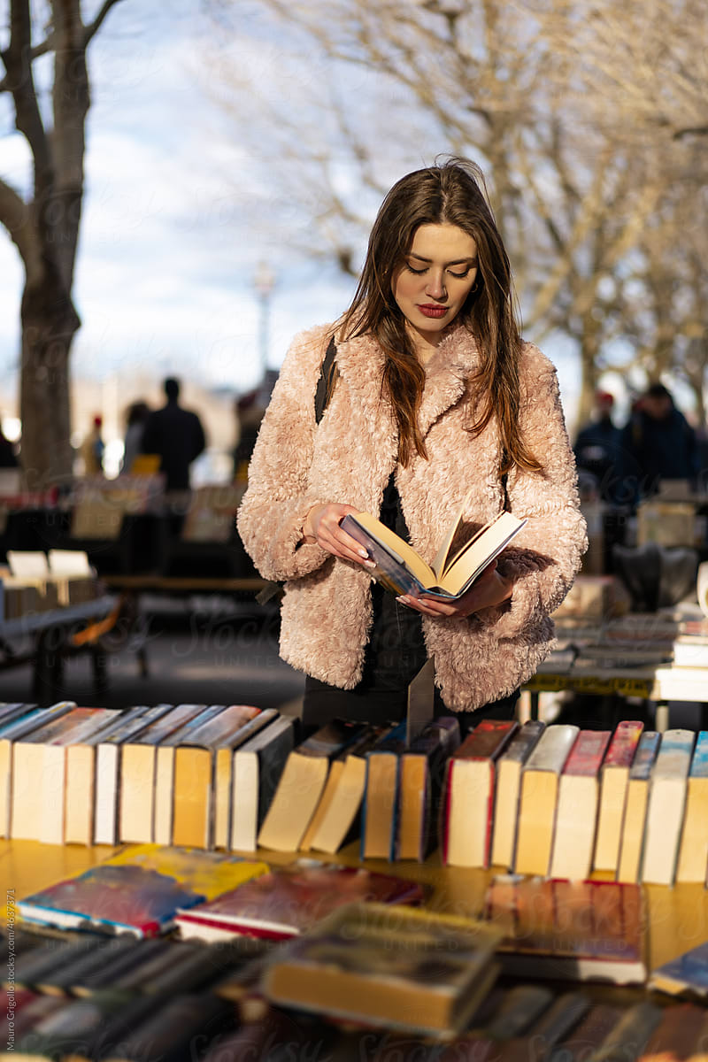 A woman reads a book in an outdoor bookstore