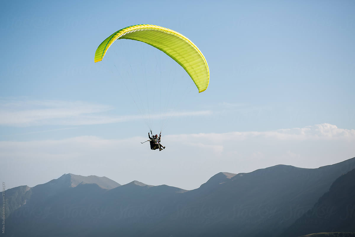 Person paragliding in high majestic mountains