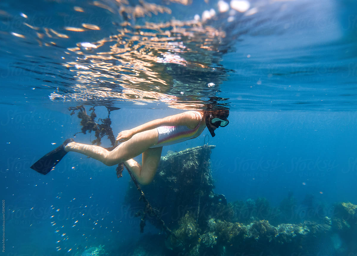 Woman snorkeling next to a sunken ship