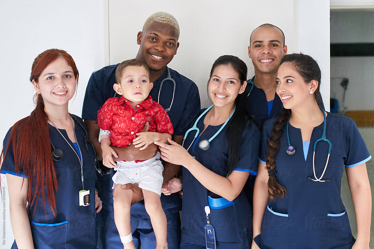 Team of young friendly doctors holding a baby patient