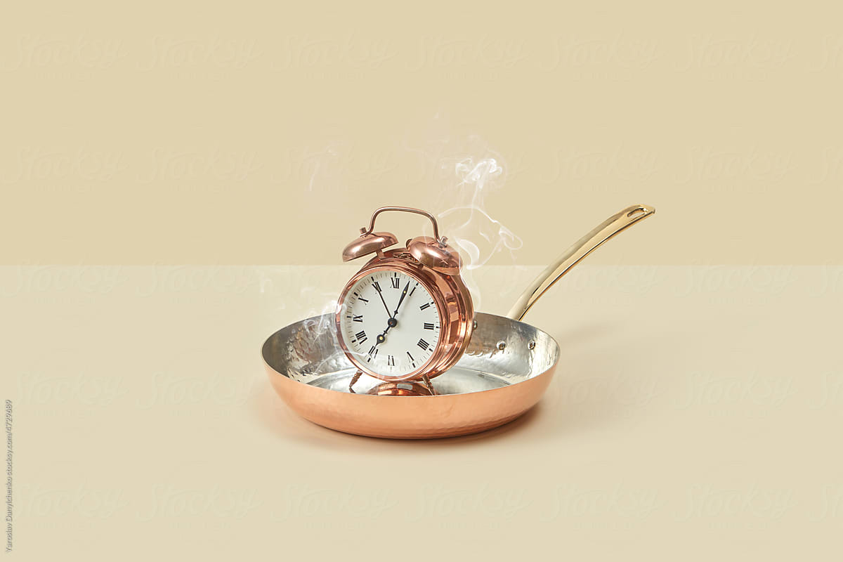 Vintage copper alarm clock in frying pan.