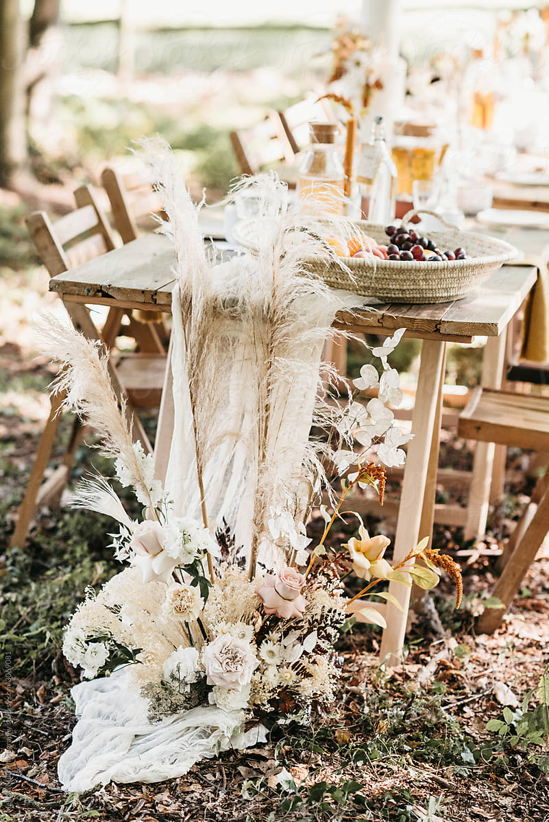 Wedding reception lunch table outdoors witth dried bohemian flowers on the side