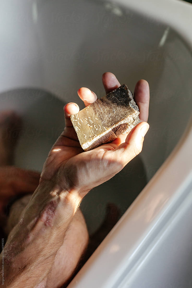 Man with psoriasis bathing with herbal soap in bathtub