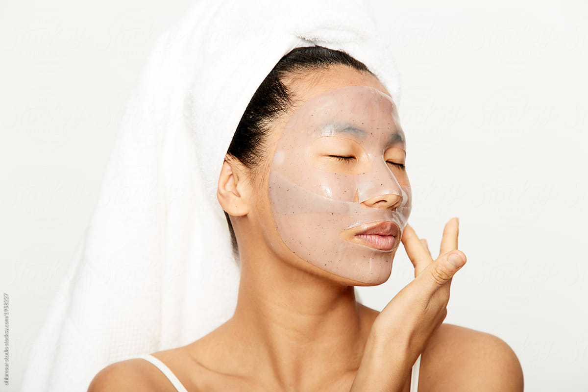 Young beautiful asian woman applying facial gel mask
