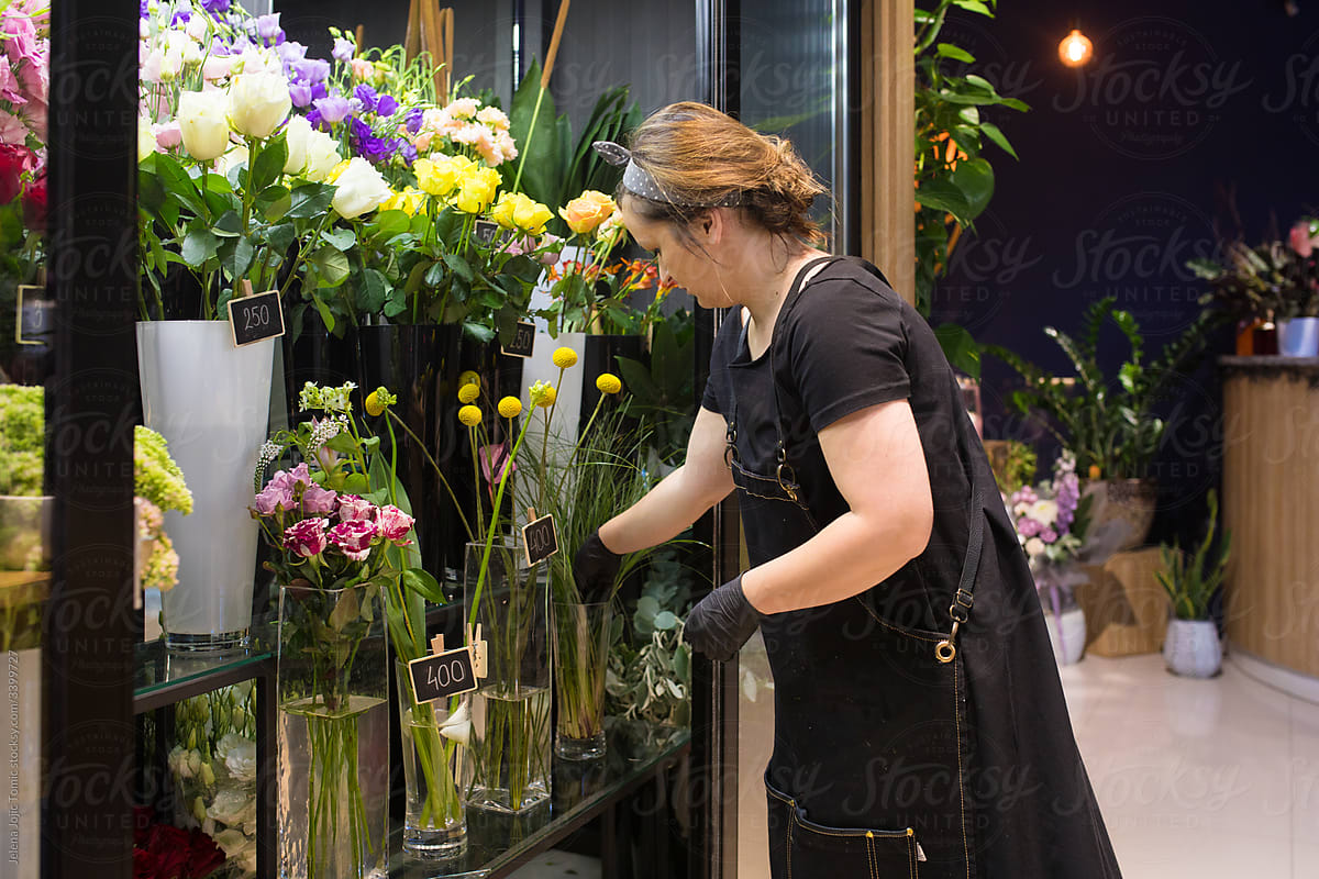 World of floristry, one day at the flower shop. The woman florist is checking out the plants in the refrigerator.