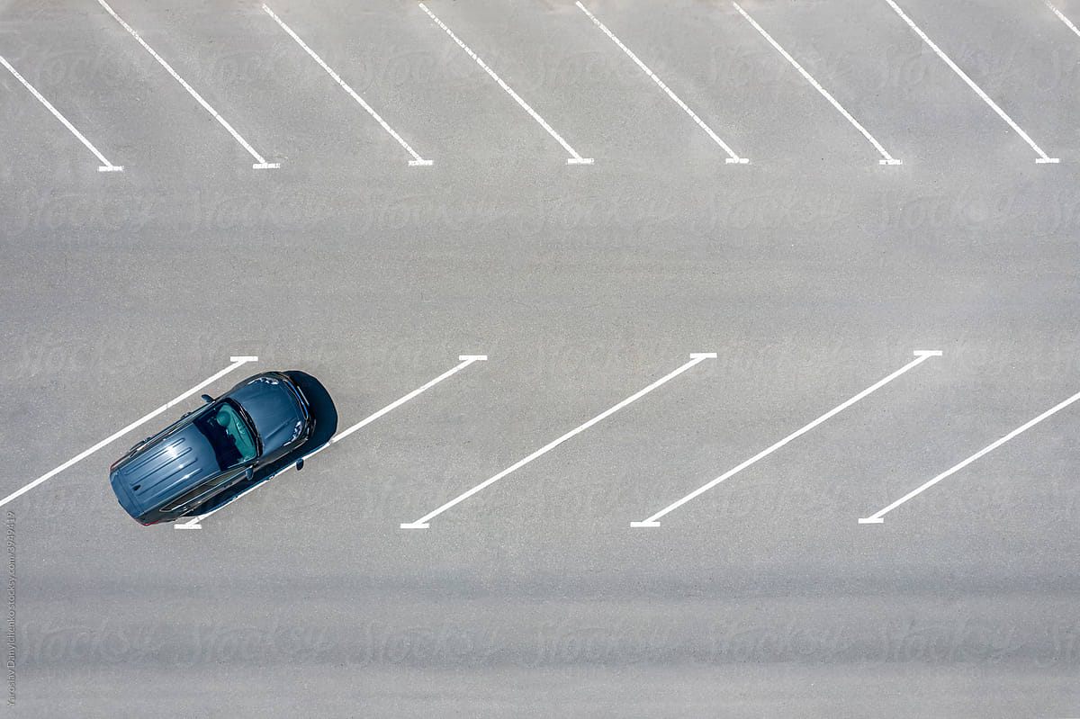 Drone view on blue car parked according to diagonal marking on asphalt
