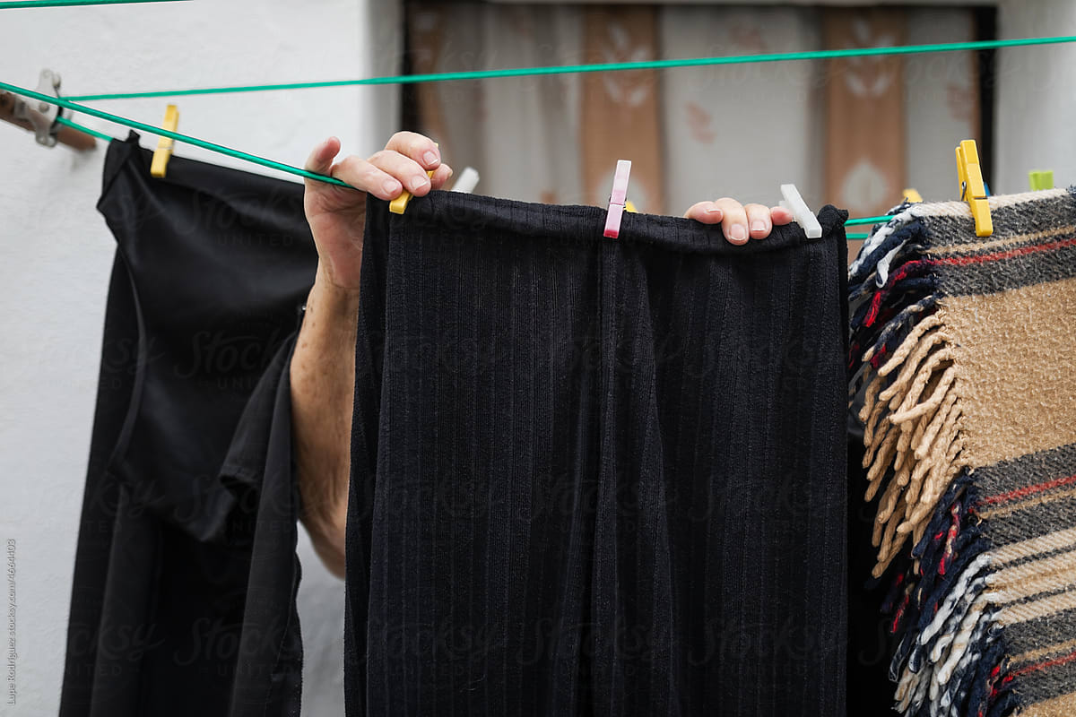 hands of old woman hanging clothes outdoors