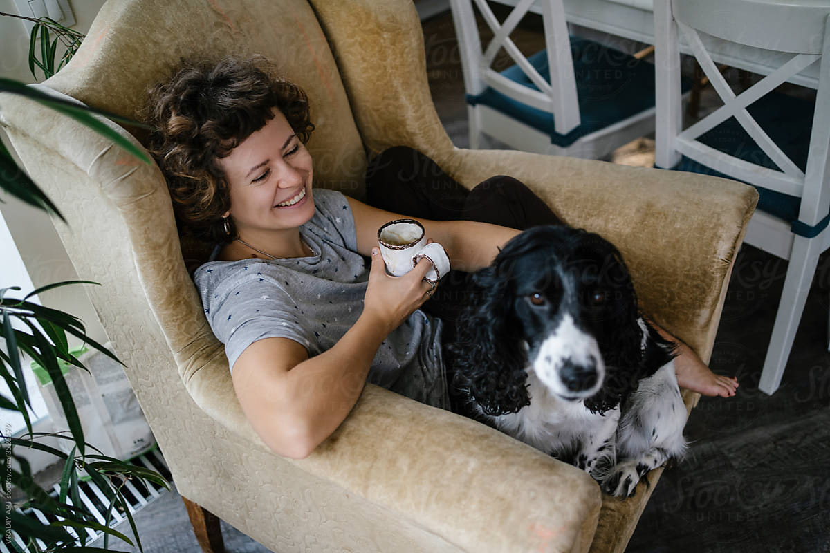 Happy woman with dog resting in armchair