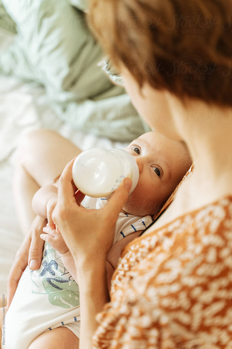 young mother feeding Newborn boy with formula from bottle