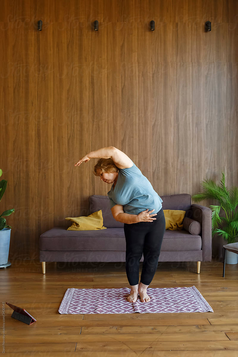 female during online yoga lesson in living room