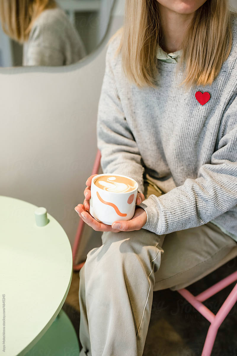 Woman sitting and holding coffee cup with latte