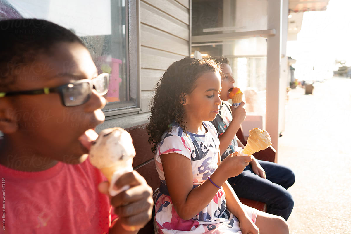 Siblings eat icecream on an outdoor bench
