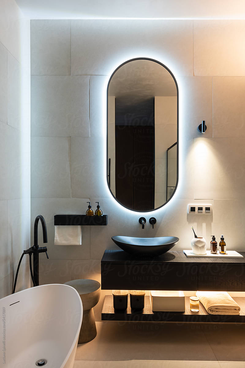 Bathroom with back lighted mirror bath, toiletry, minimalist lighting