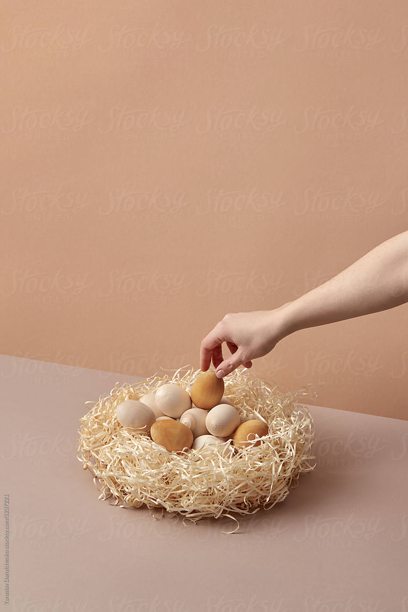 Wooden Easter eggs laid by woman's hand in nest.