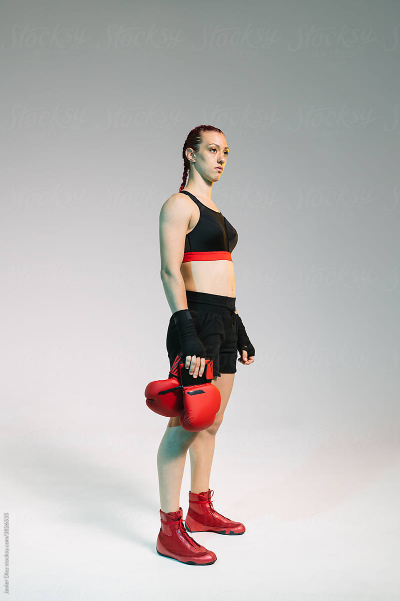 Young female boxer pose near bag on a sports training in a gym. Stock Photo  | Adobe Stock
