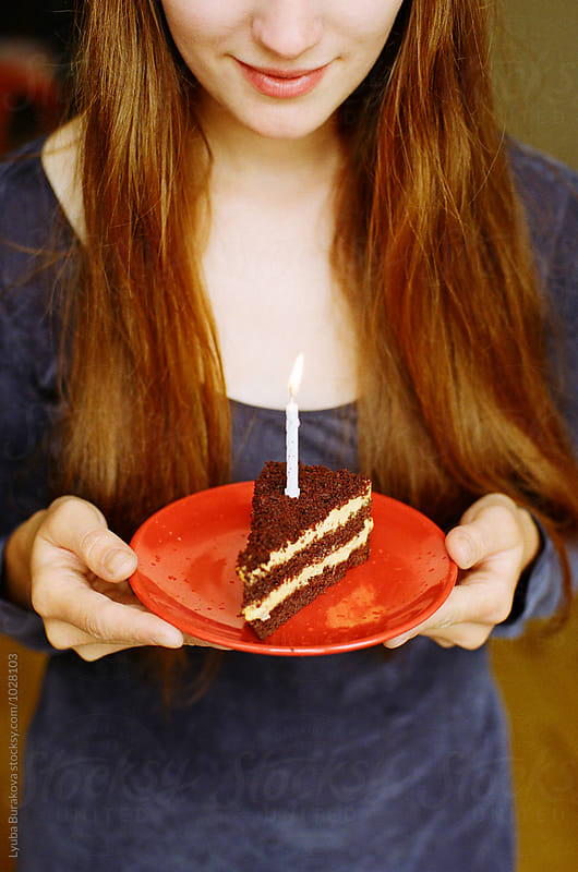 Young woman holding plate with a piece of birthday cake