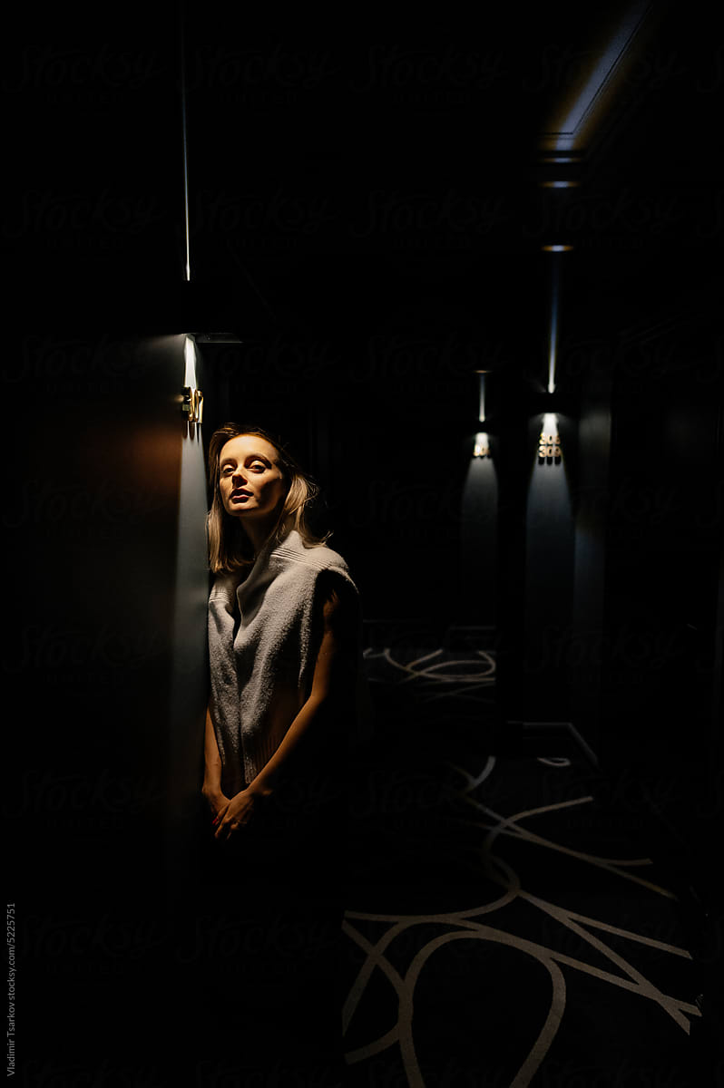Young woman standing under glowing lamp