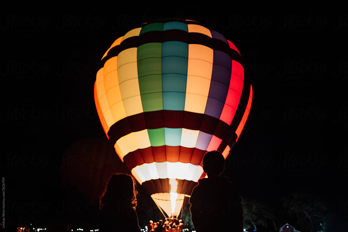 Young girl and boy watching a hot air balloon glow.