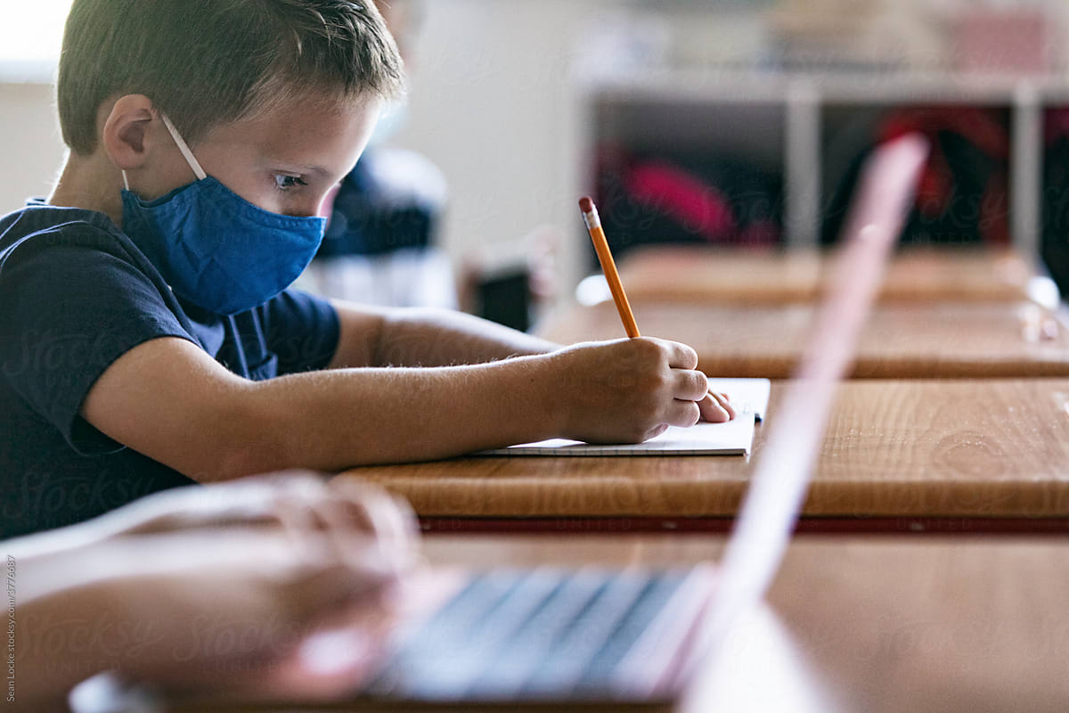 School: Boy Student Writing Essay At Desk