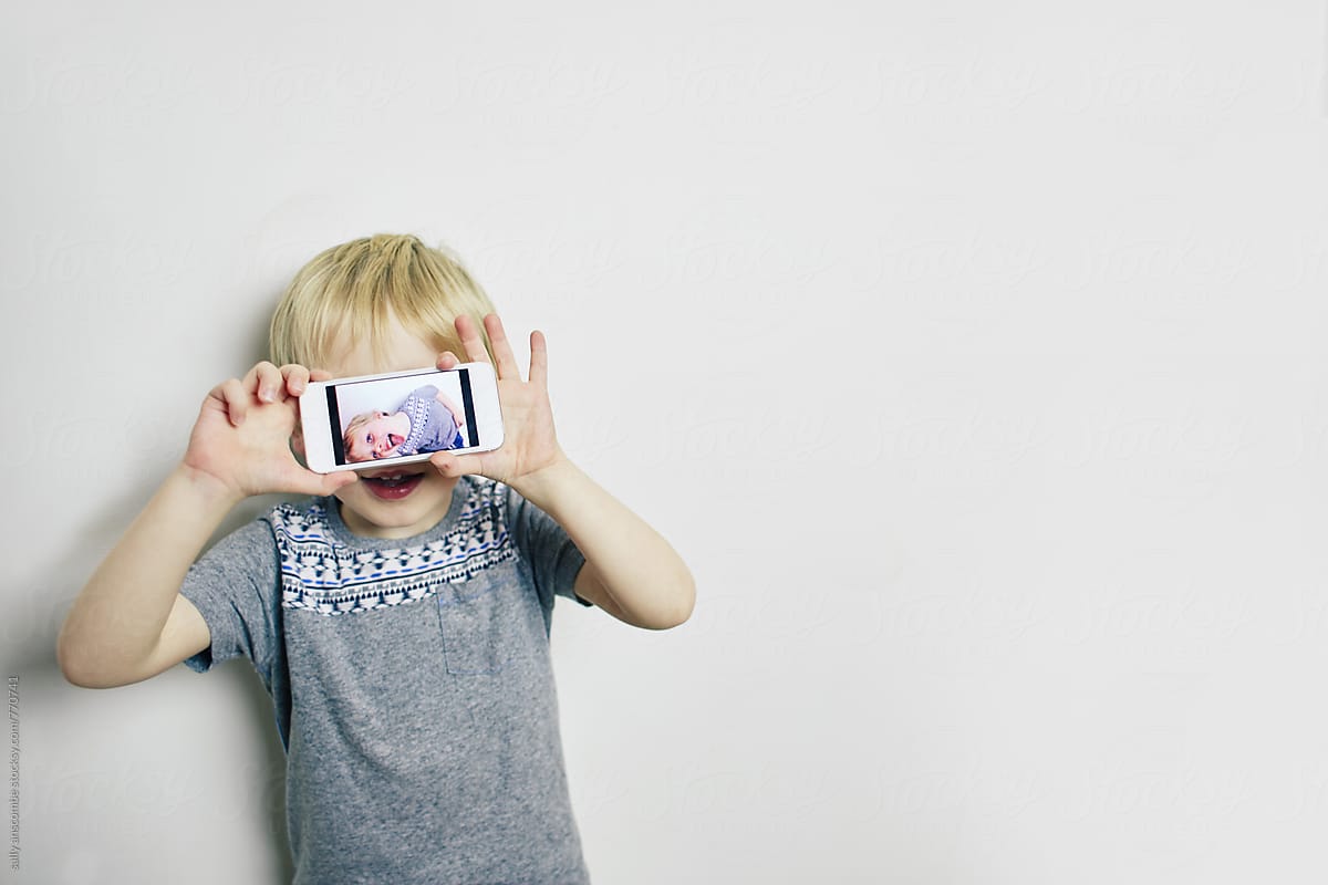Little boy holding up a phone with a photo on it