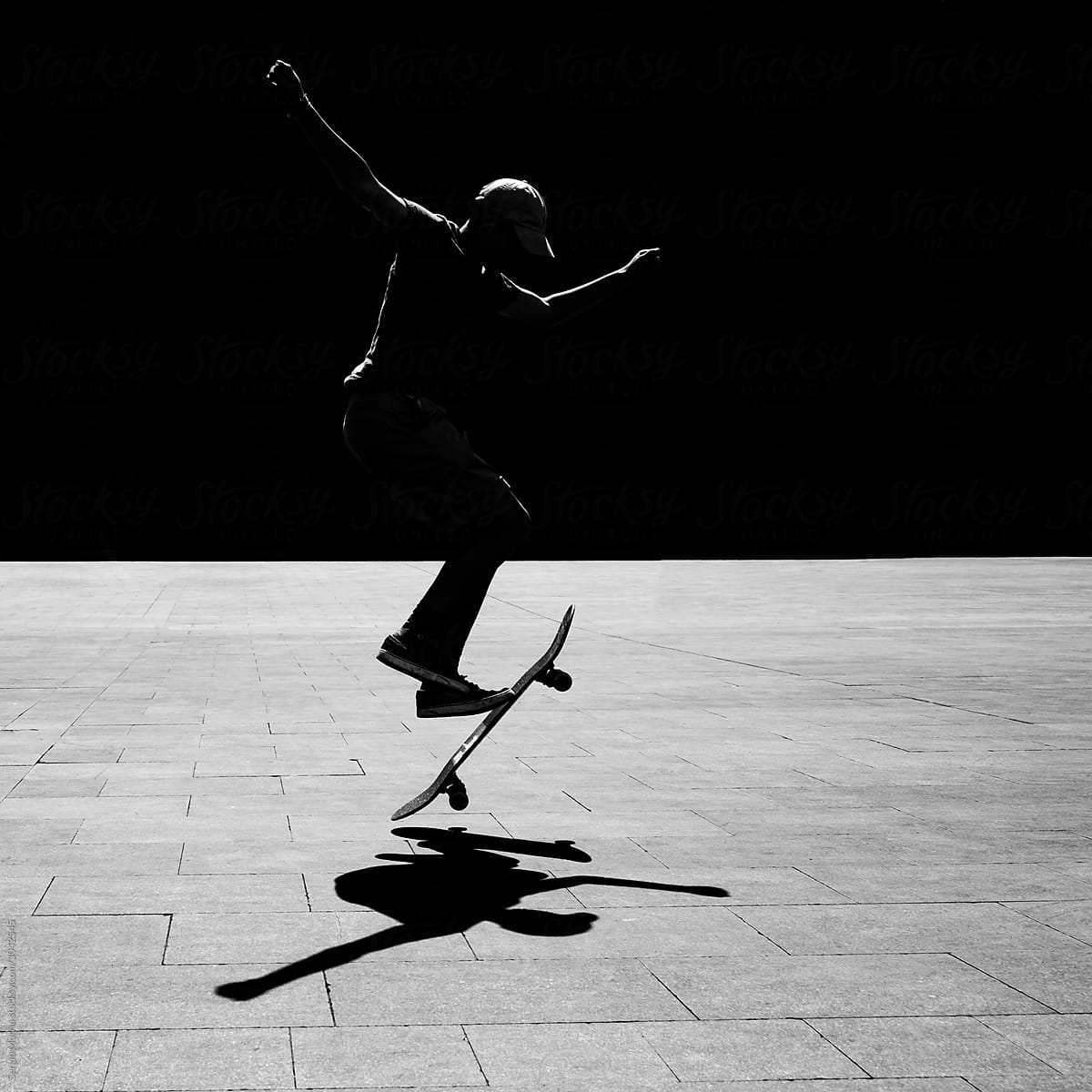 Backlit silhouette performing skateboard stunts