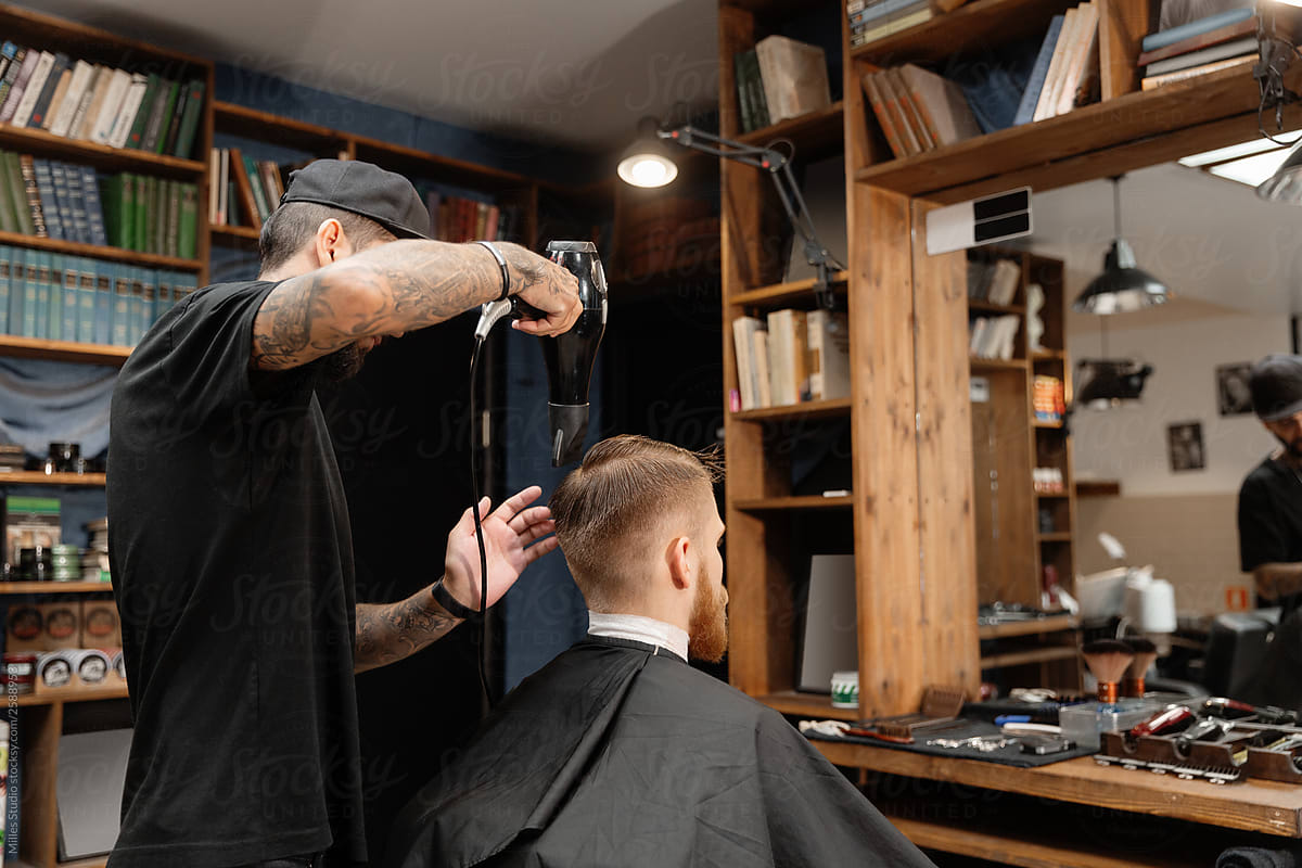 Brutal barber drying hair of man in salon
