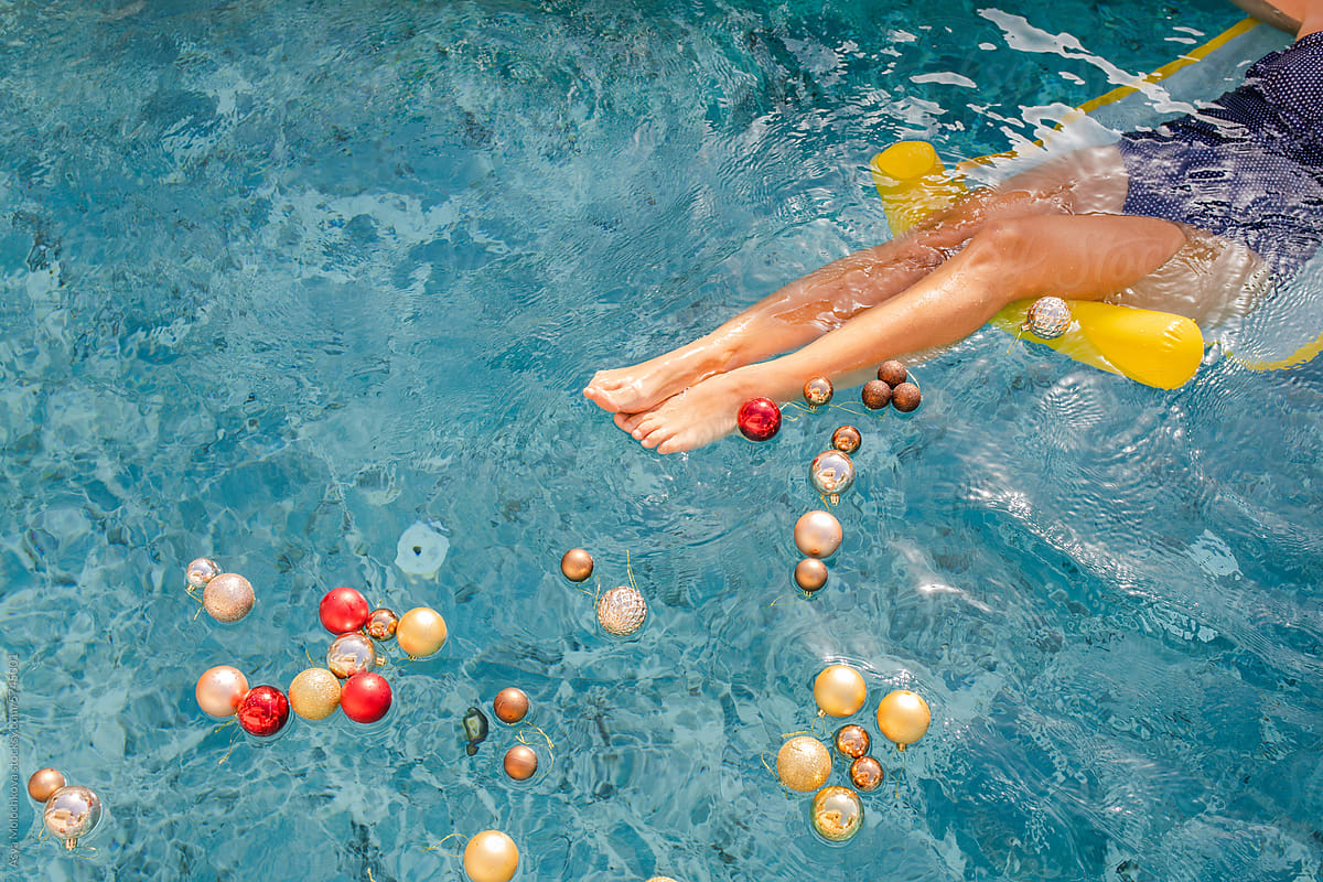 Woman\'s legs floating in swimming pool with Christmas decorations