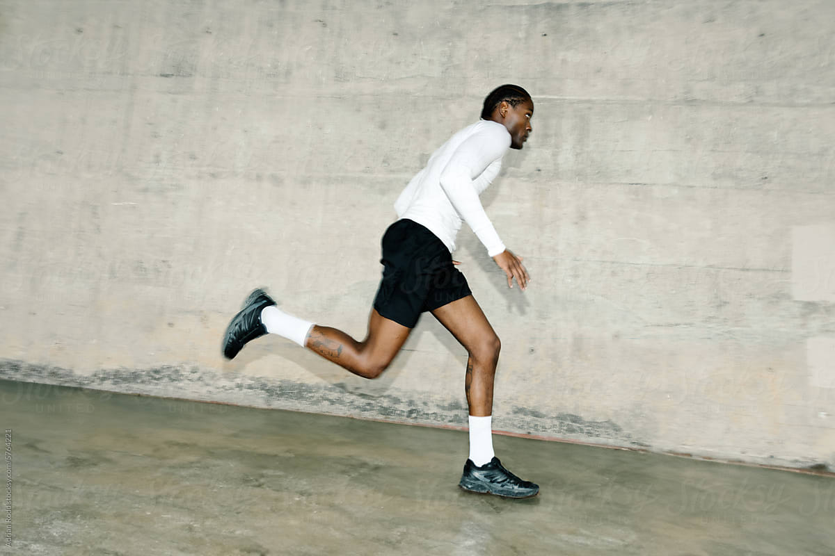 A Black man, dressed in athletic attire, engages in sprints