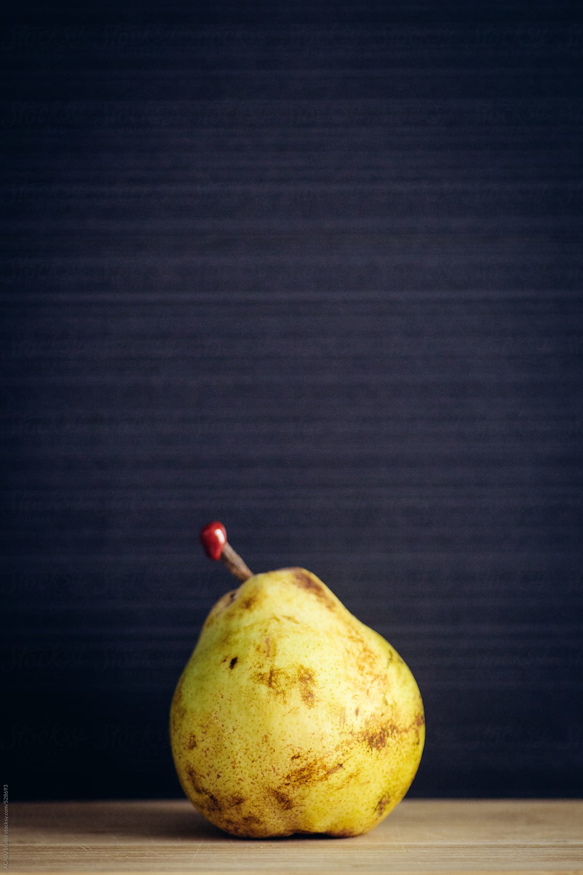 Yellow pear with red seal on black background