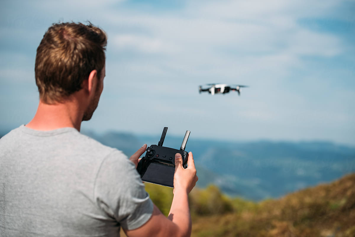 Man controlling flight of drone in hilly terrain