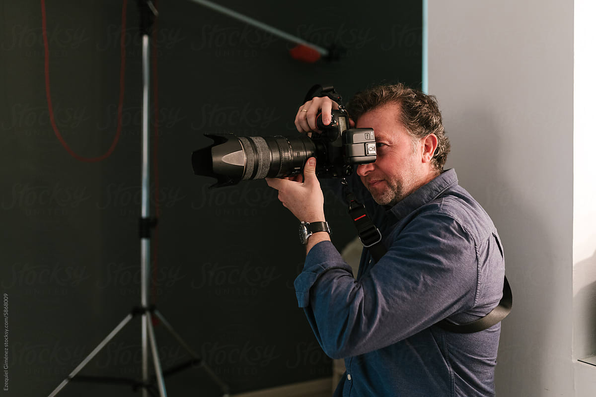 Male photographer taking photo on camera in studio