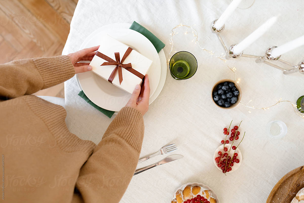 A woman packs a Christmas gift on a festive table