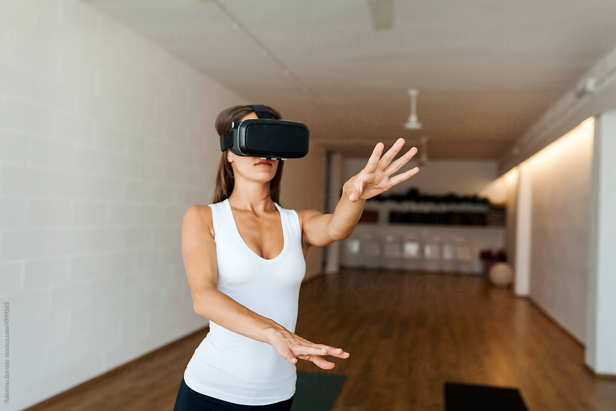 Fit woman practicing yoga wearing VR glasses