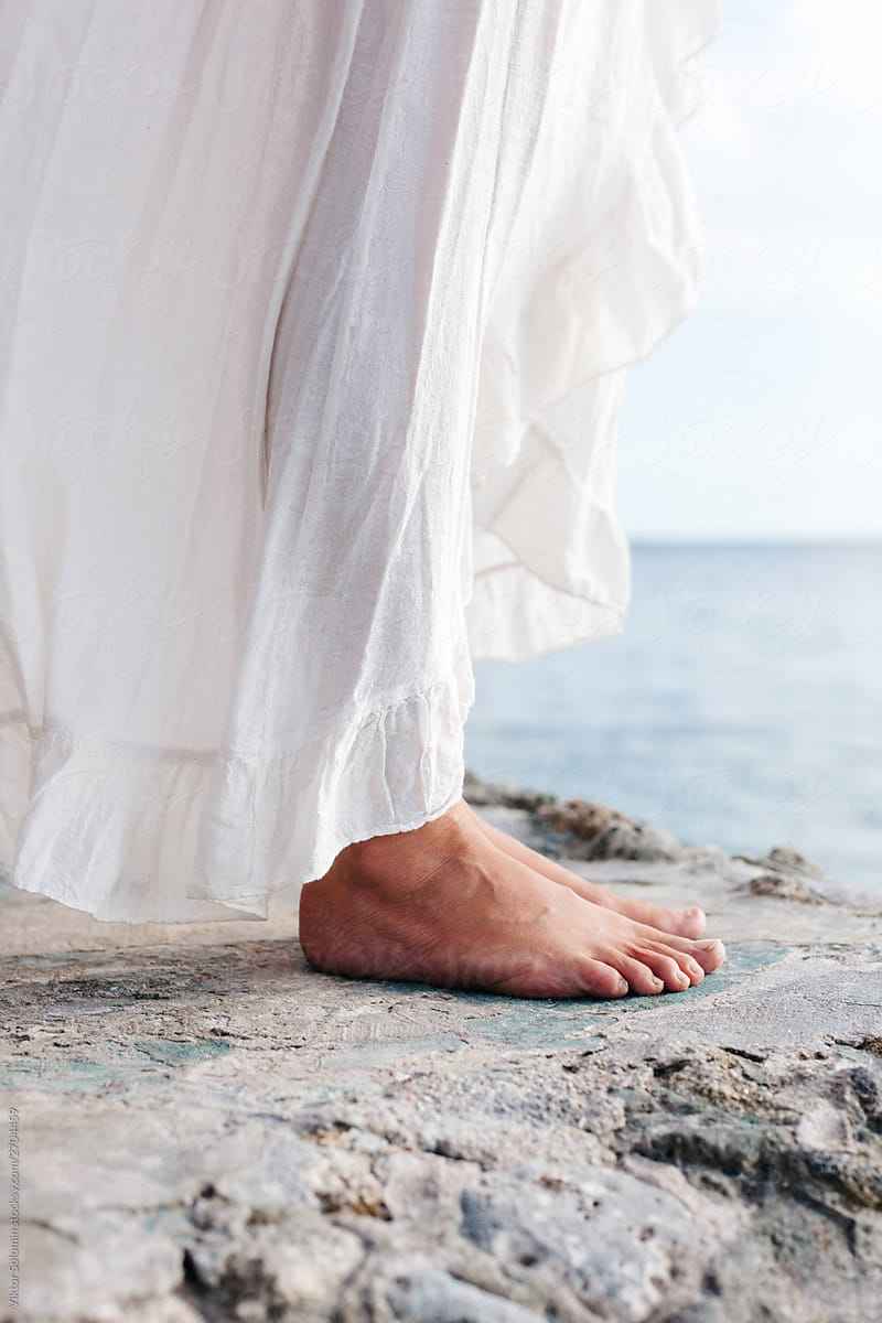 Closeup of barefoot woman\'s legs standing on the rock in summer near the sea