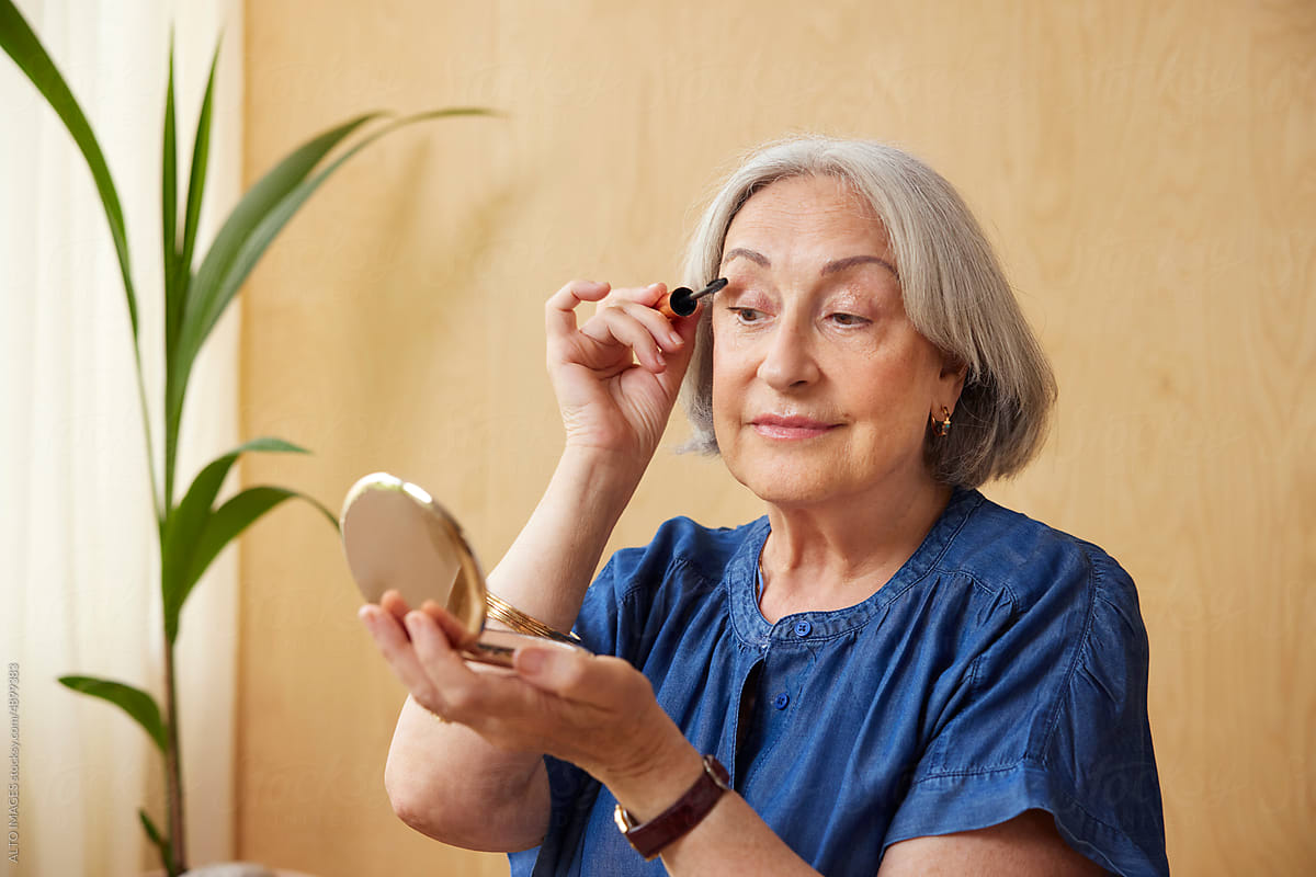 Senior woman applying makeup at home
