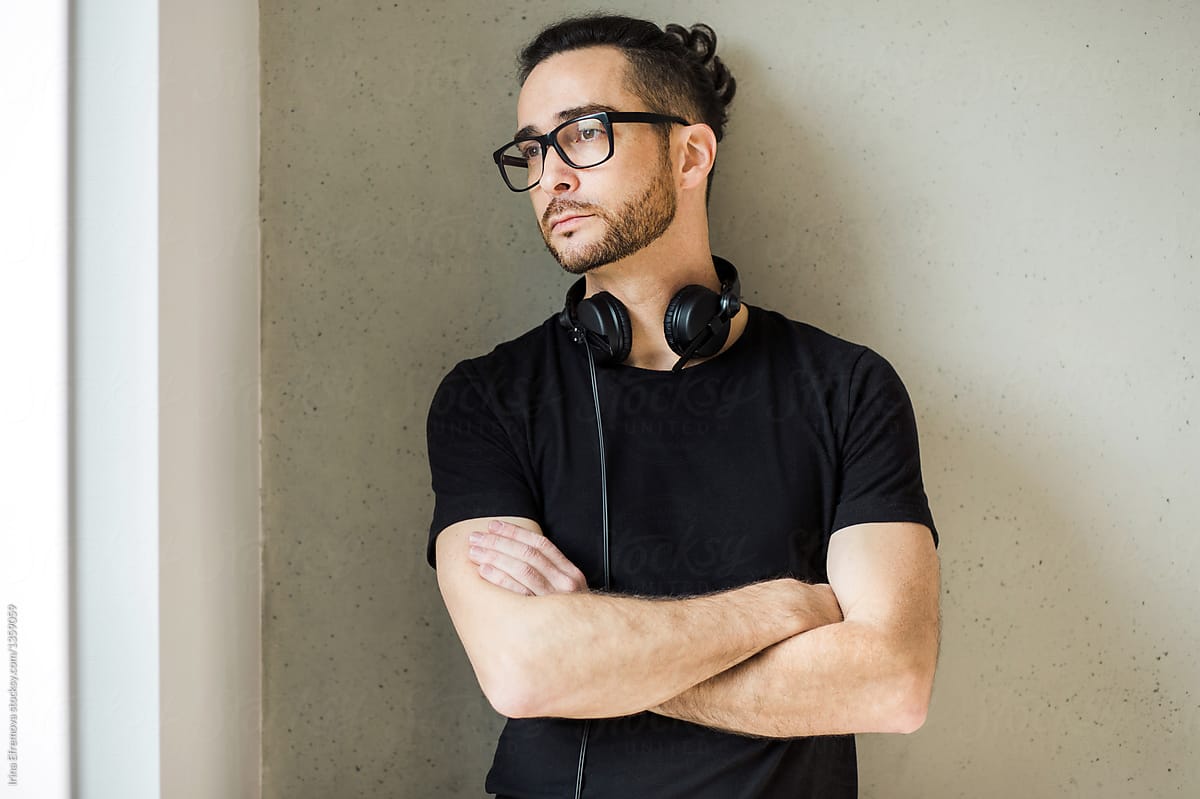 Handsome man in his early 40 in a black t-shirt wearing glasses and headphones around his neck