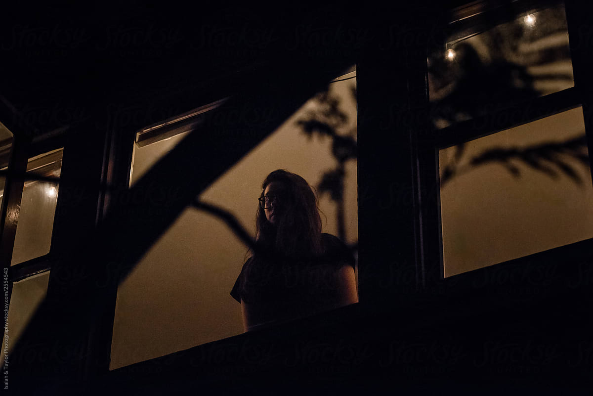 Person silhouette standing in a house window