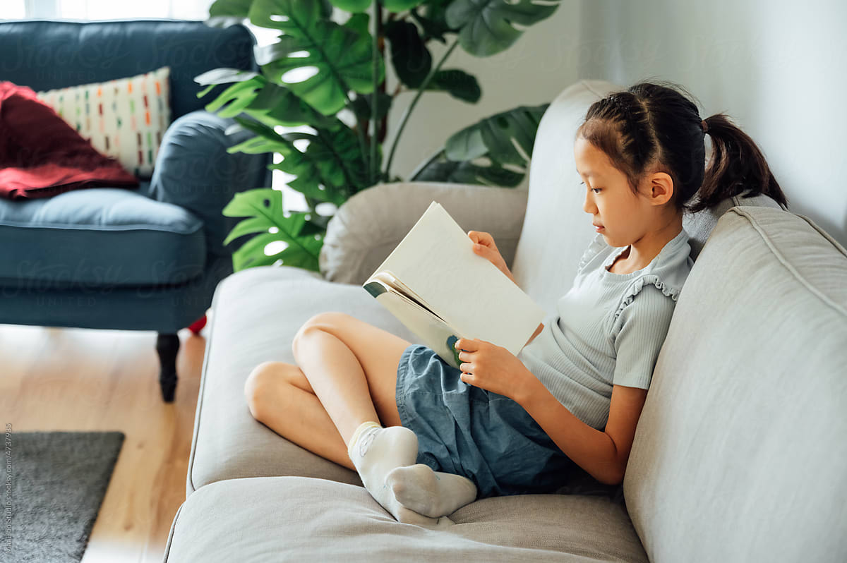 Cute girl reading books on couch