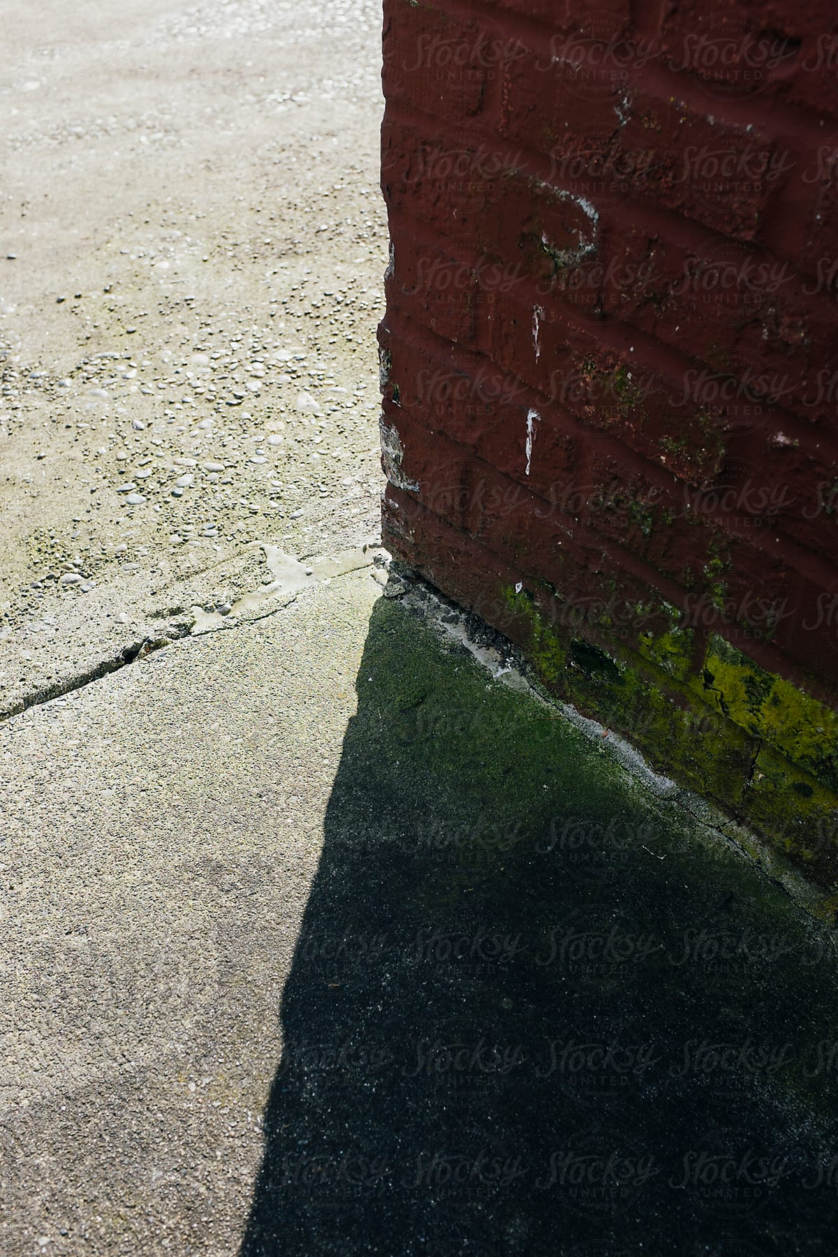 Detail of building corner casting shadow on urban sidewalk
