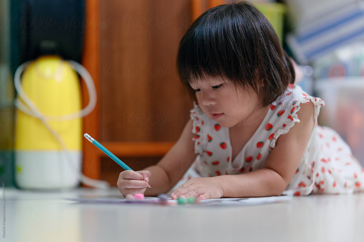 Adorable little child draws on paper with pencil