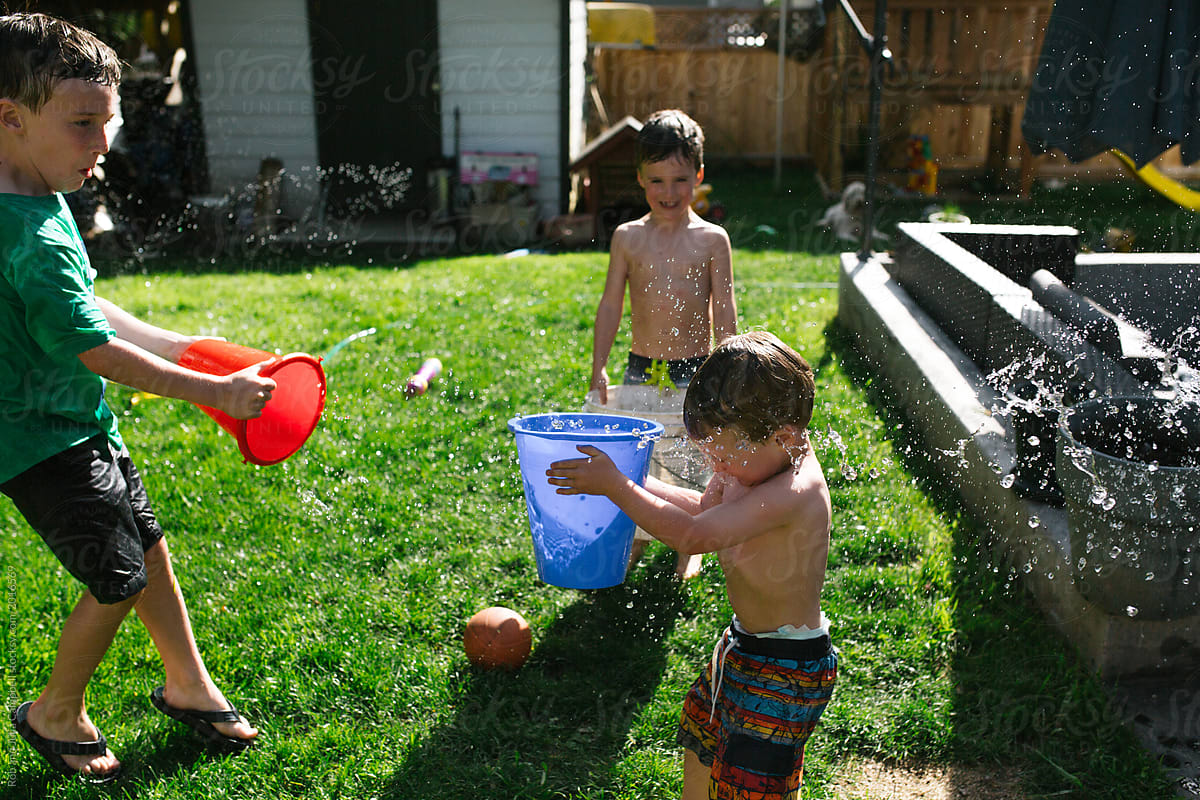 Boy splashing brother with bucket of water