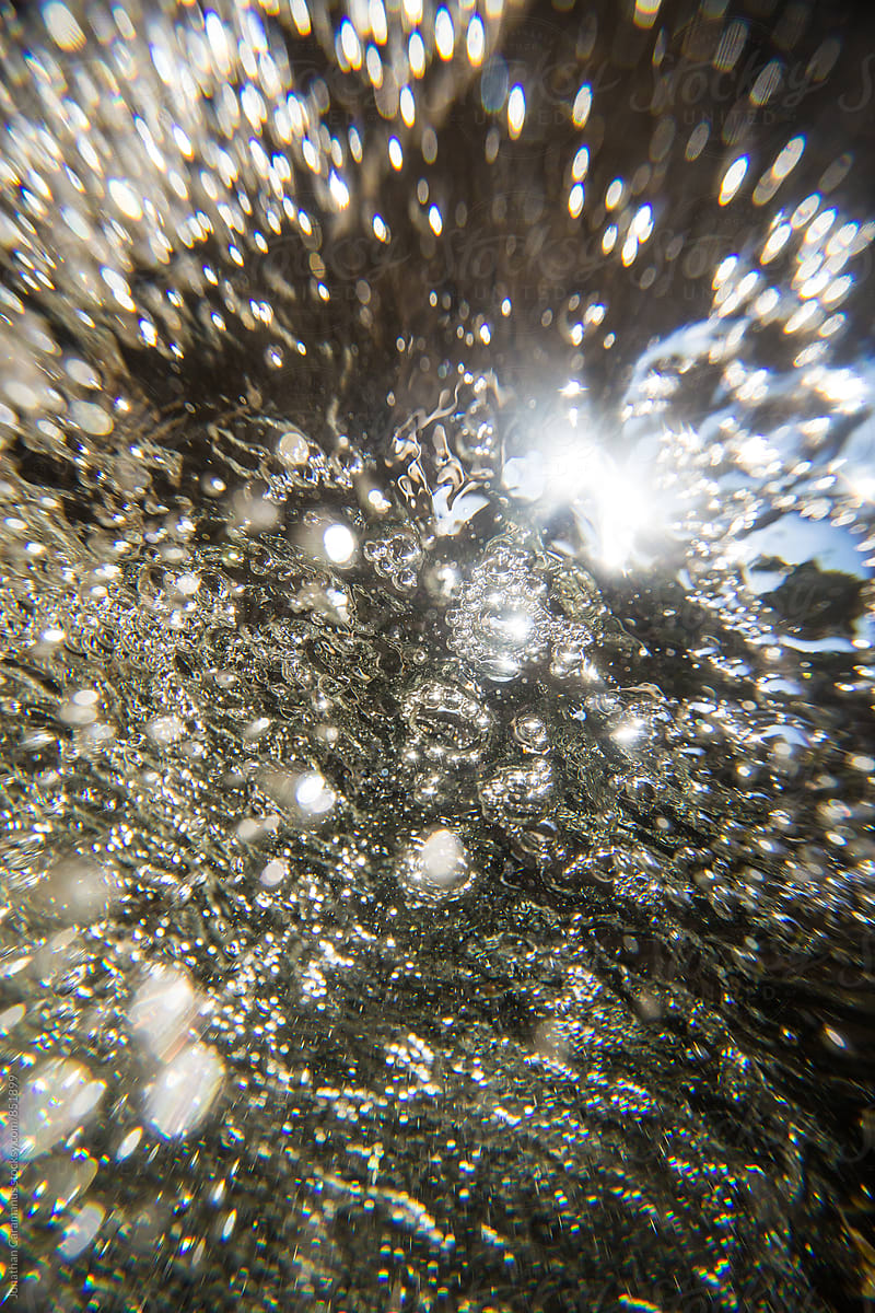 Diamond bubbles sparkle underwater and glitter in the sunlight under a waterfall