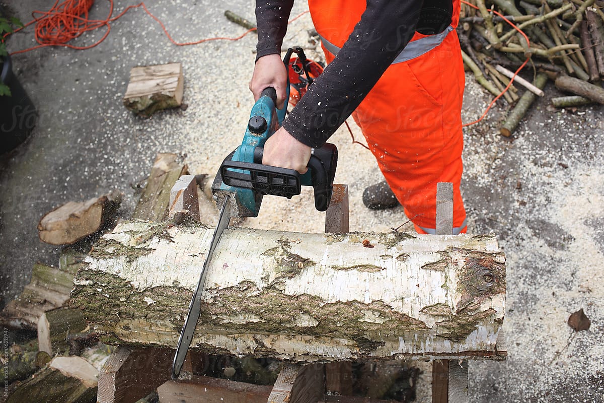Man using a chainsaw to cut trunks in pieces