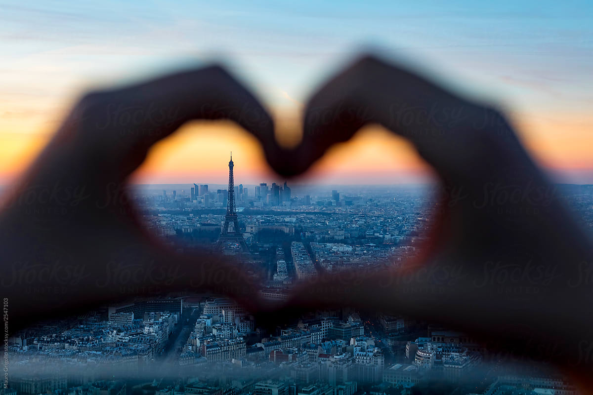 Heart-shaped hands with Paris cityscape