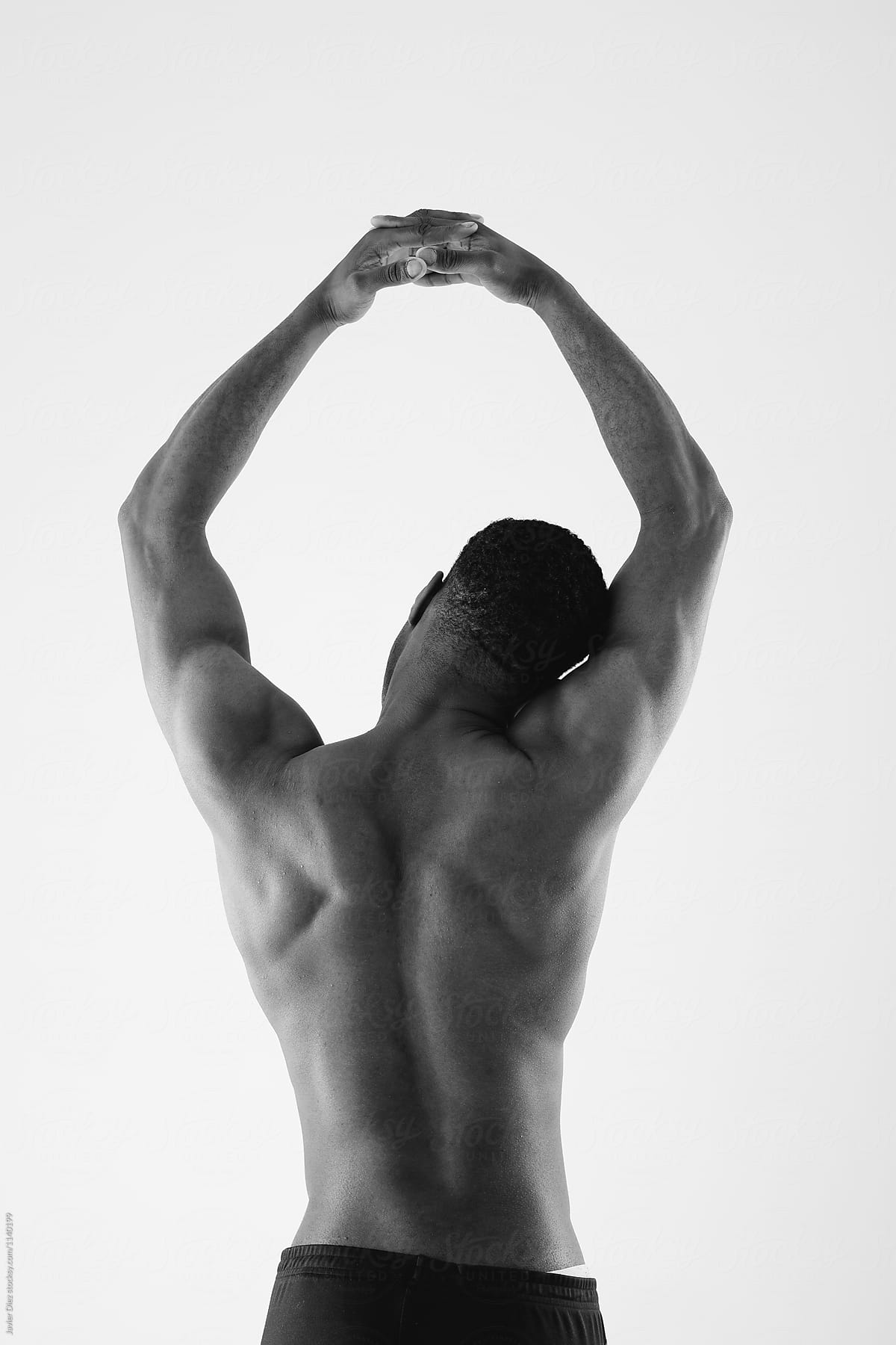 Black and white of topless man stretching arms above head